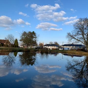 Reflections of clouds in a village pond